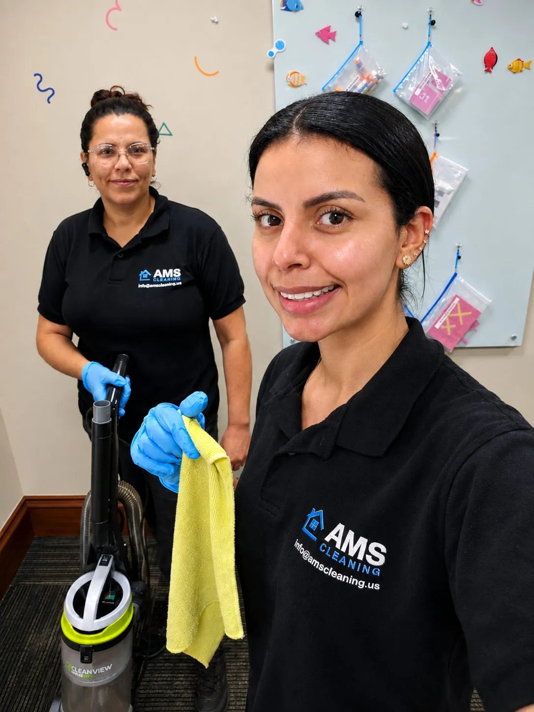 Both founders in AMS-branded shirts smiling on the job with vacuum and microfiber cloth